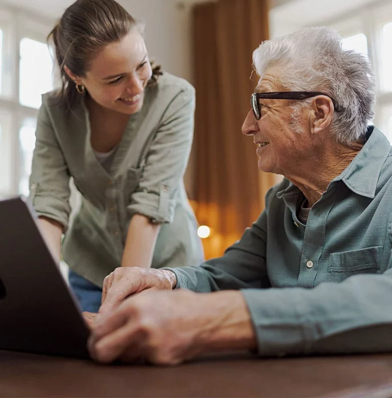 woman and older gentleman reviewing information on a tablet and smiling at each other