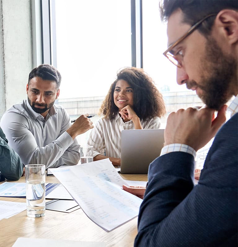 Three people sitting around a table at a board meeting