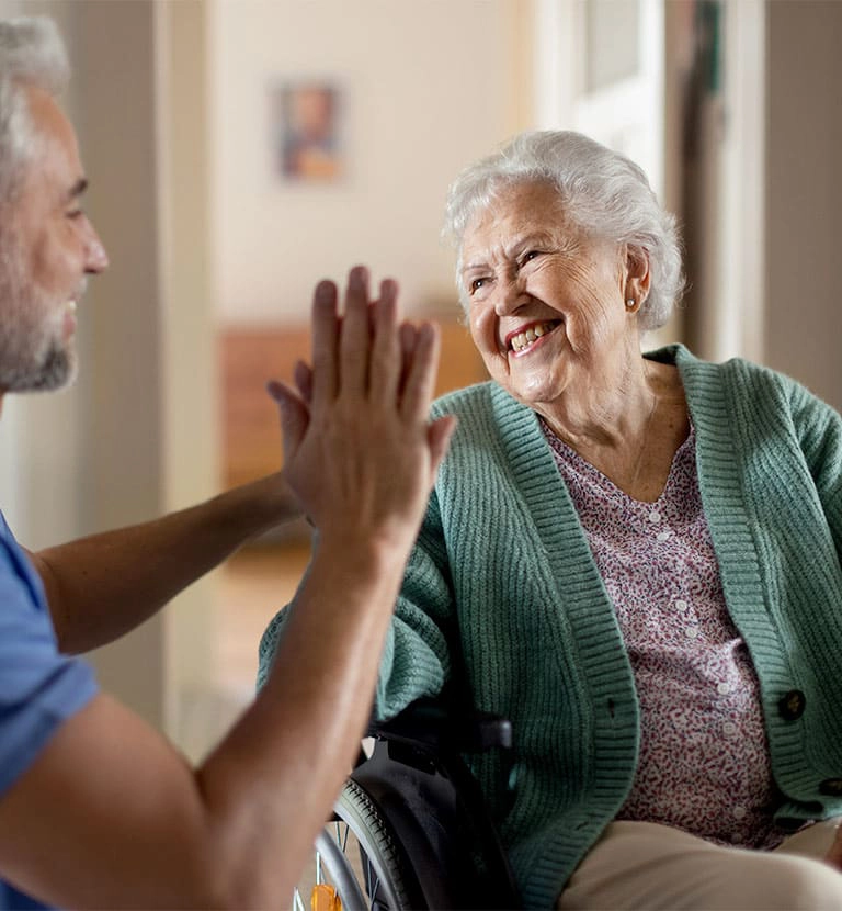 older woman and gentleman looking at each other and smiling while giving a high five