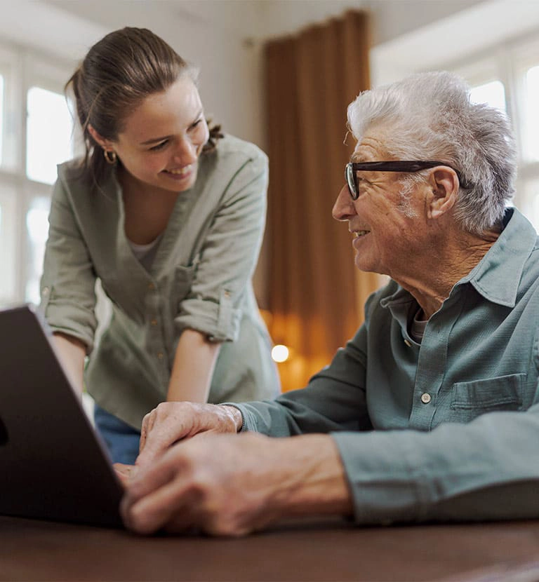 woman and older gentleman reviewing information on a tablet and smiling at each other